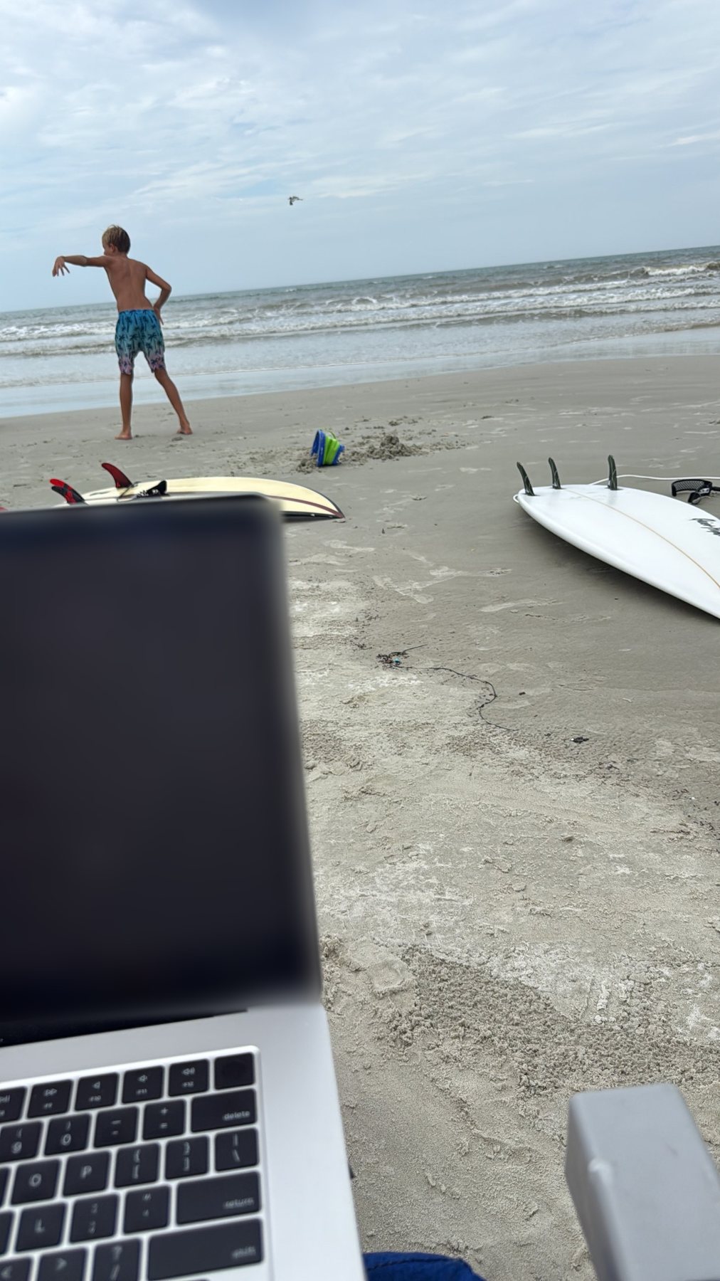 Surfboards and a laptop on the beach on a family day