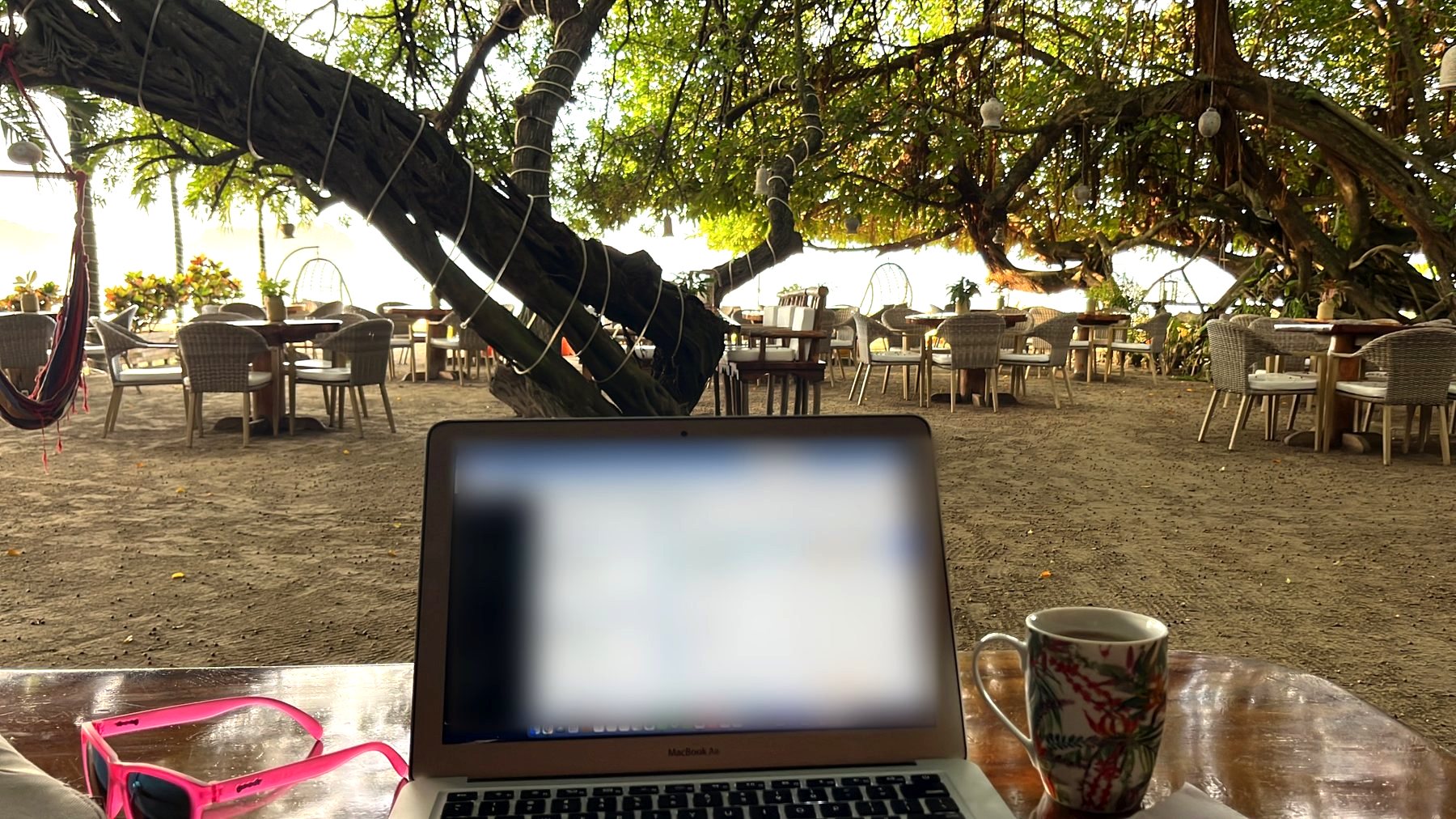 Brooke working from a beachfront table with coffee